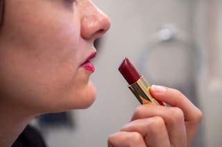 A woman putting on red lipstick