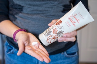 A woman squeezing lotion from a bottle