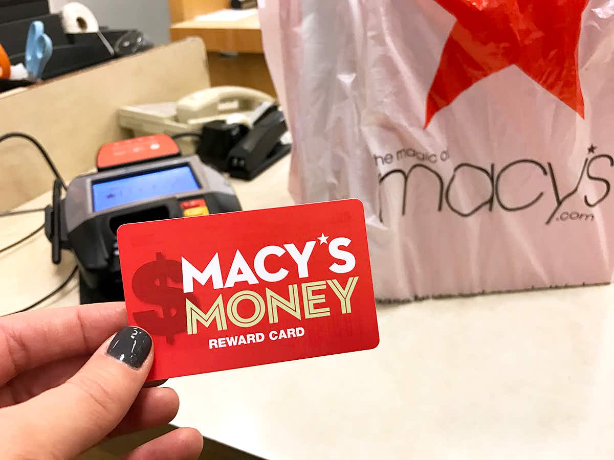 hand holding Macy's Money card at checkout with bag