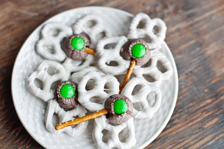 Some white chocolate pretzels as clovers stuck together with a chocolate kiss and green m&m