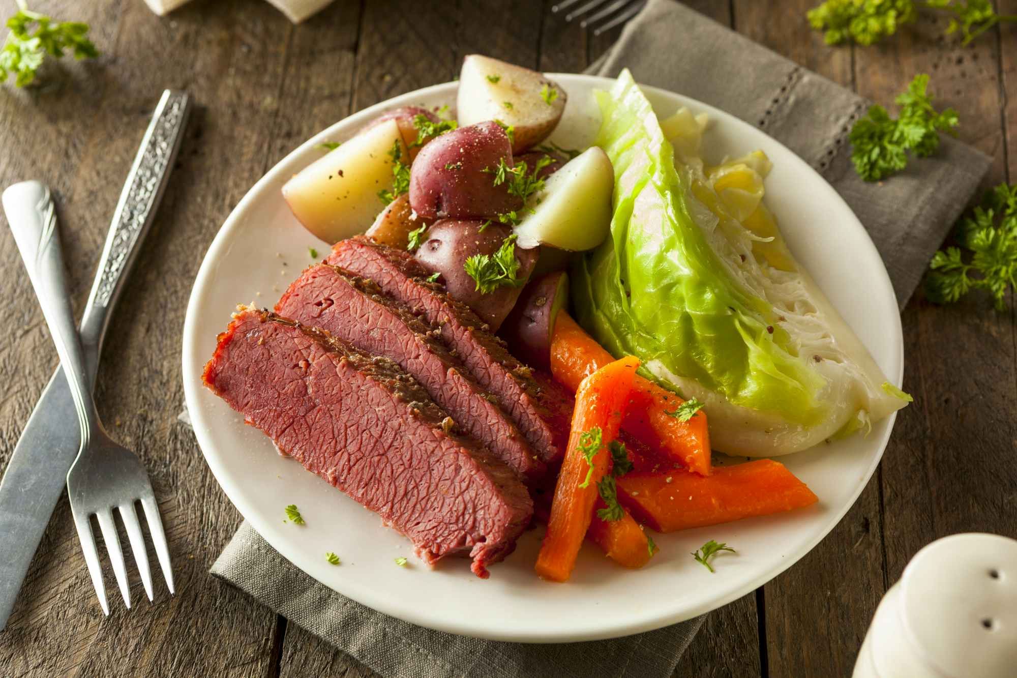 A corned beef and cabbage dinner on a plate with carrots and potatoes