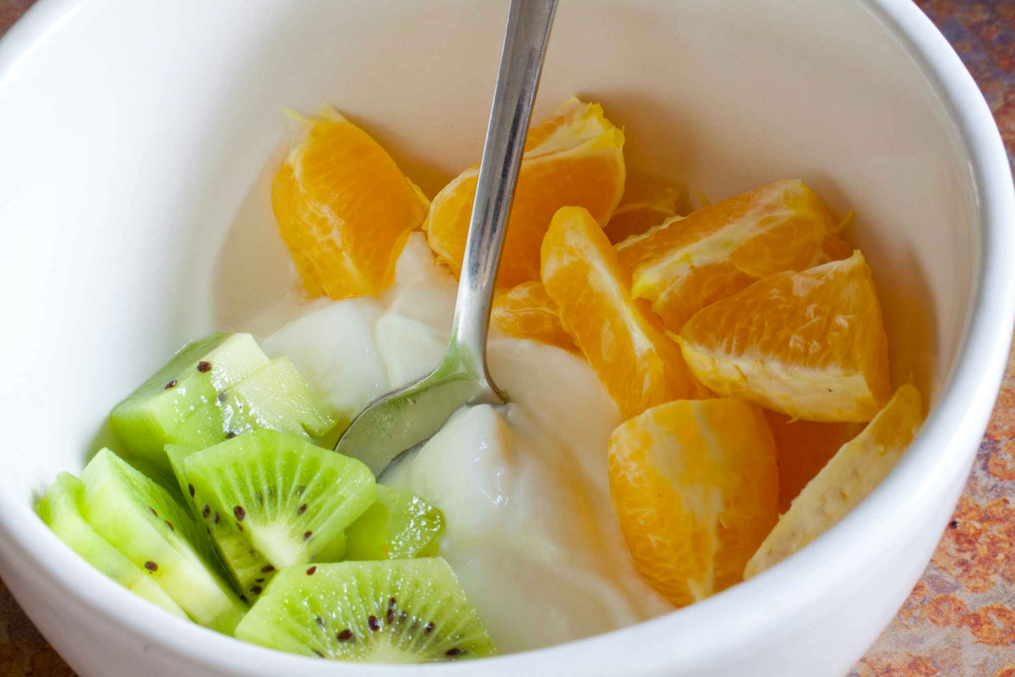A close up on a bowl with kiwi, yogurt, and mandarin oranges arranged to look like the Irish flag