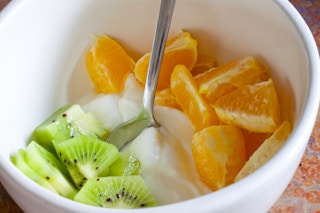 A close up on a bowl with kiwi, yogurt, and mandarin oranges arranged to look like the Irish flag