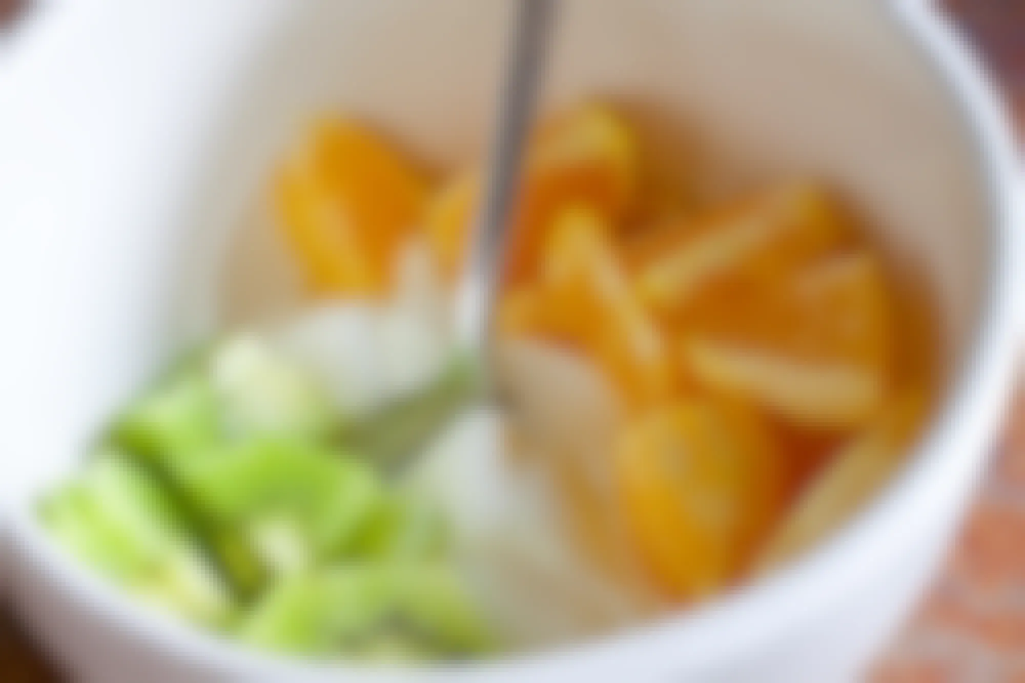 A close up on a bowl with kiwi, yogurt, and mandarin oranges arranged to look like the Irish flag