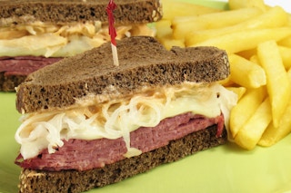 A pumpernickel Ruben sandwich with fries