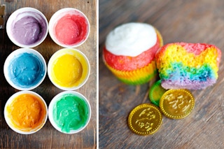 Cups of different colored batter next to some rainbow cupcakes