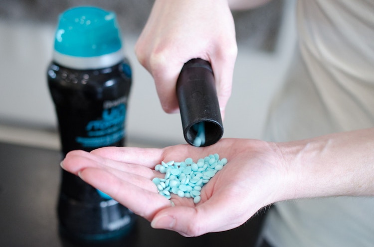 Someone using a vacuum to suck up some Downy Unstoppables from their hand