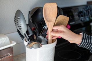 Wooden spoons in a container next to a stove