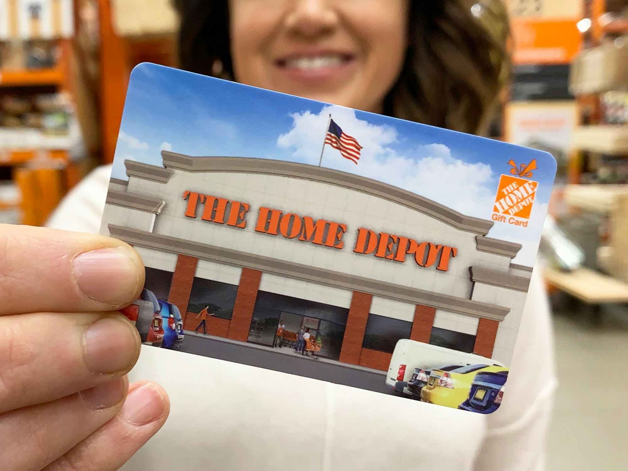 a person holding a Home Depot gift card in front of them