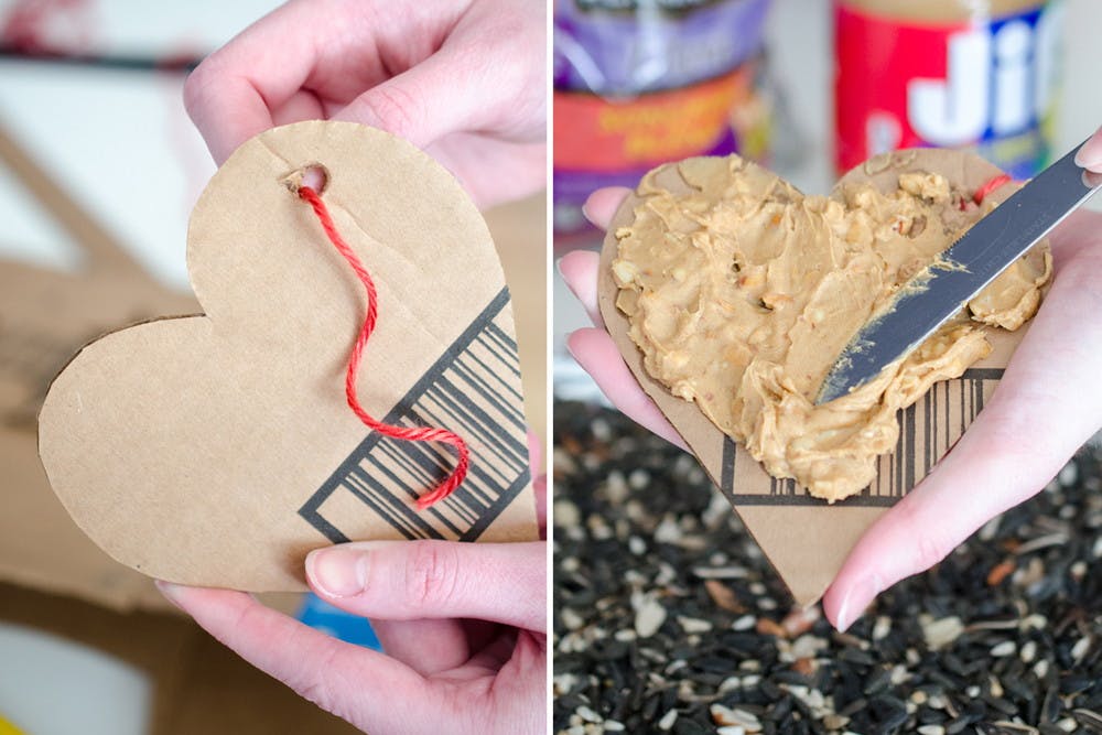 Someone putting string through a cardboard heart and spreading peanut butter on it