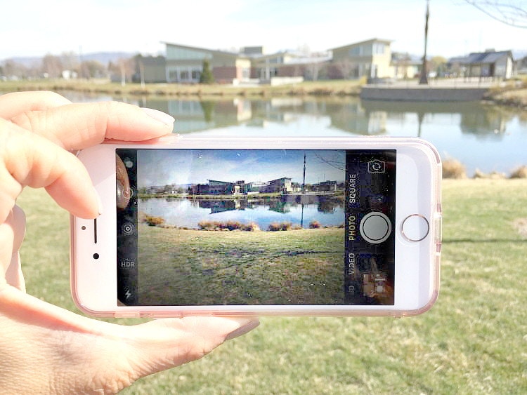 A person taking a picture of a lake with their phone.