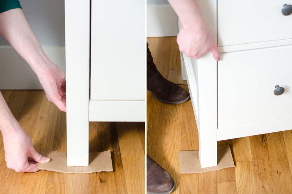 A person lifting a piece of furniture onto a small piece of cardboard.