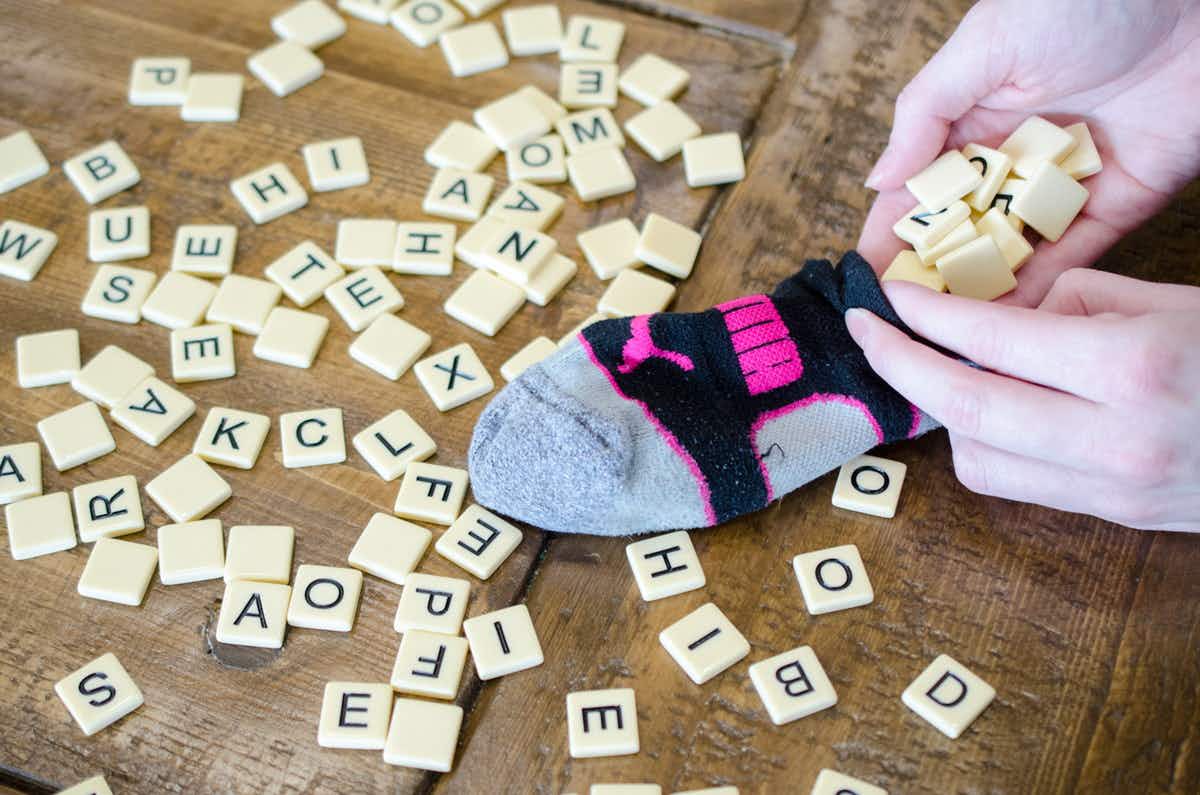 A person putting scrabble pieces into a sock.