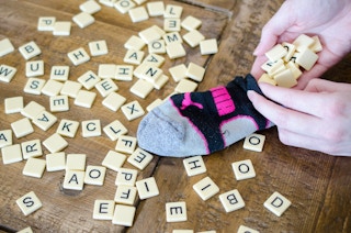A person putting scrabble pieces into a sock.