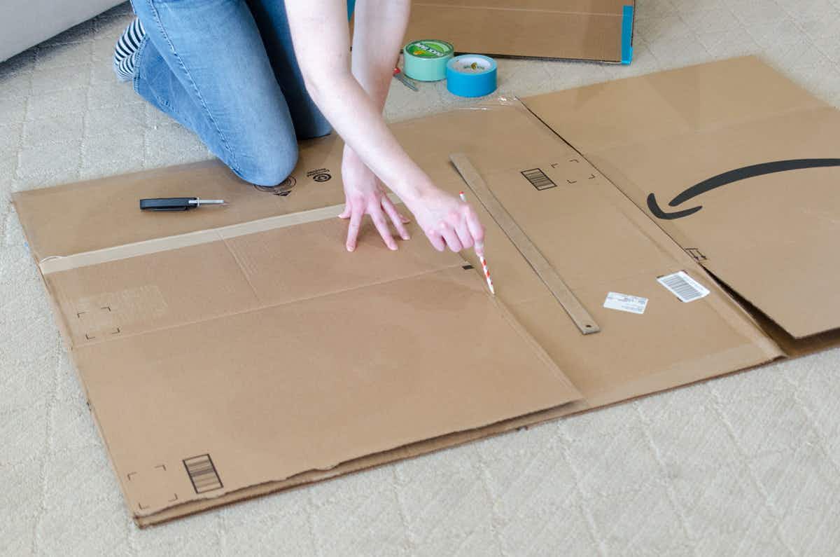 A person drawing on a cardboard box with a pencil.