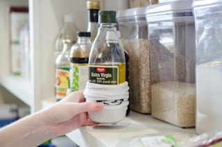 A person holding a bottle of oil with a sock on it.