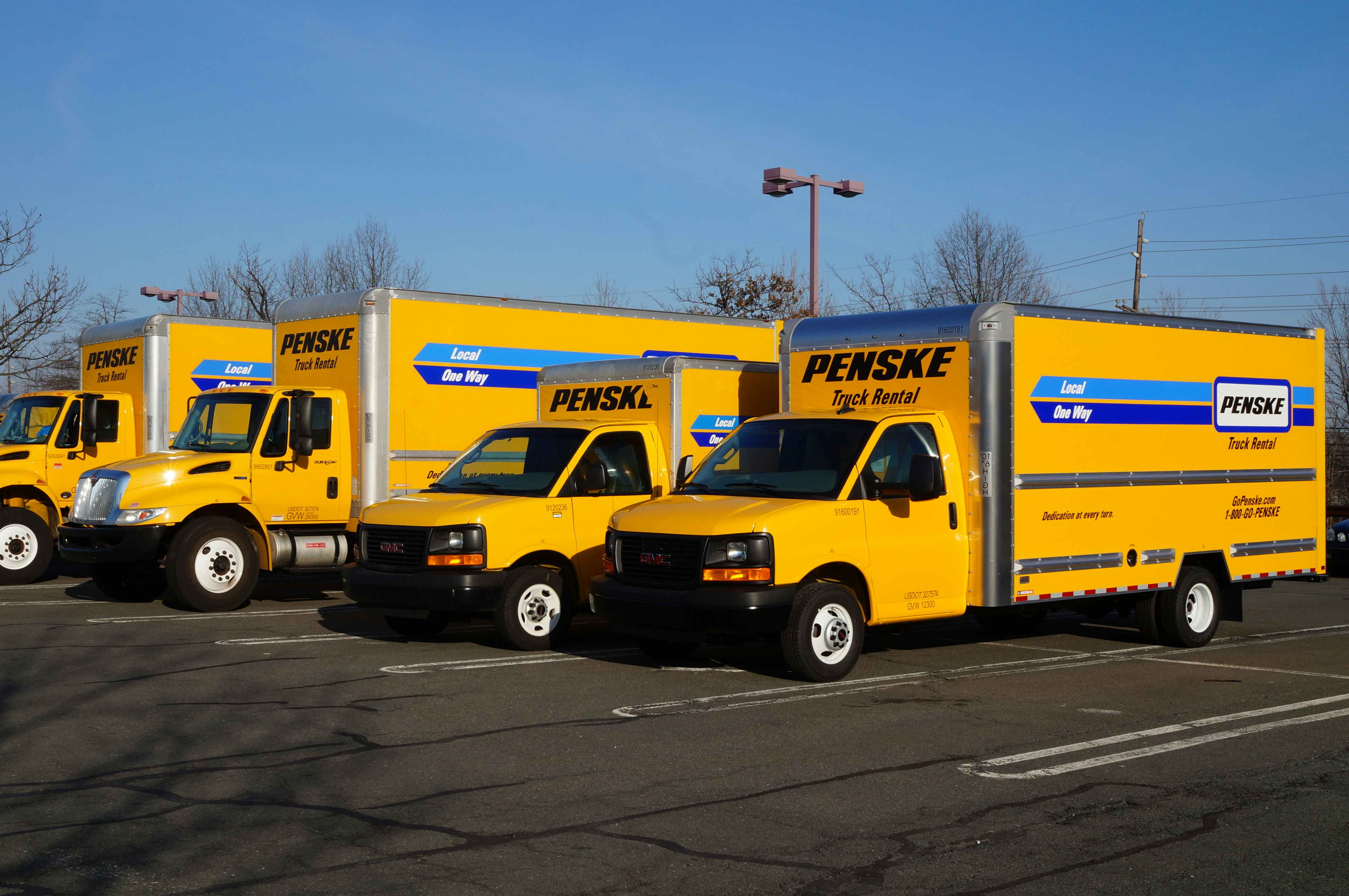 A row of Penske trucks parked in a parking lot