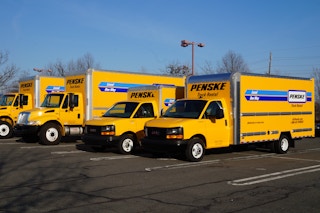 A row of Penske trucks parked in a parking lot