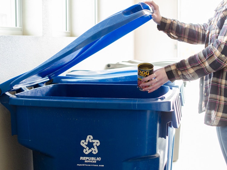 a person recycling cans into a recycling bin 