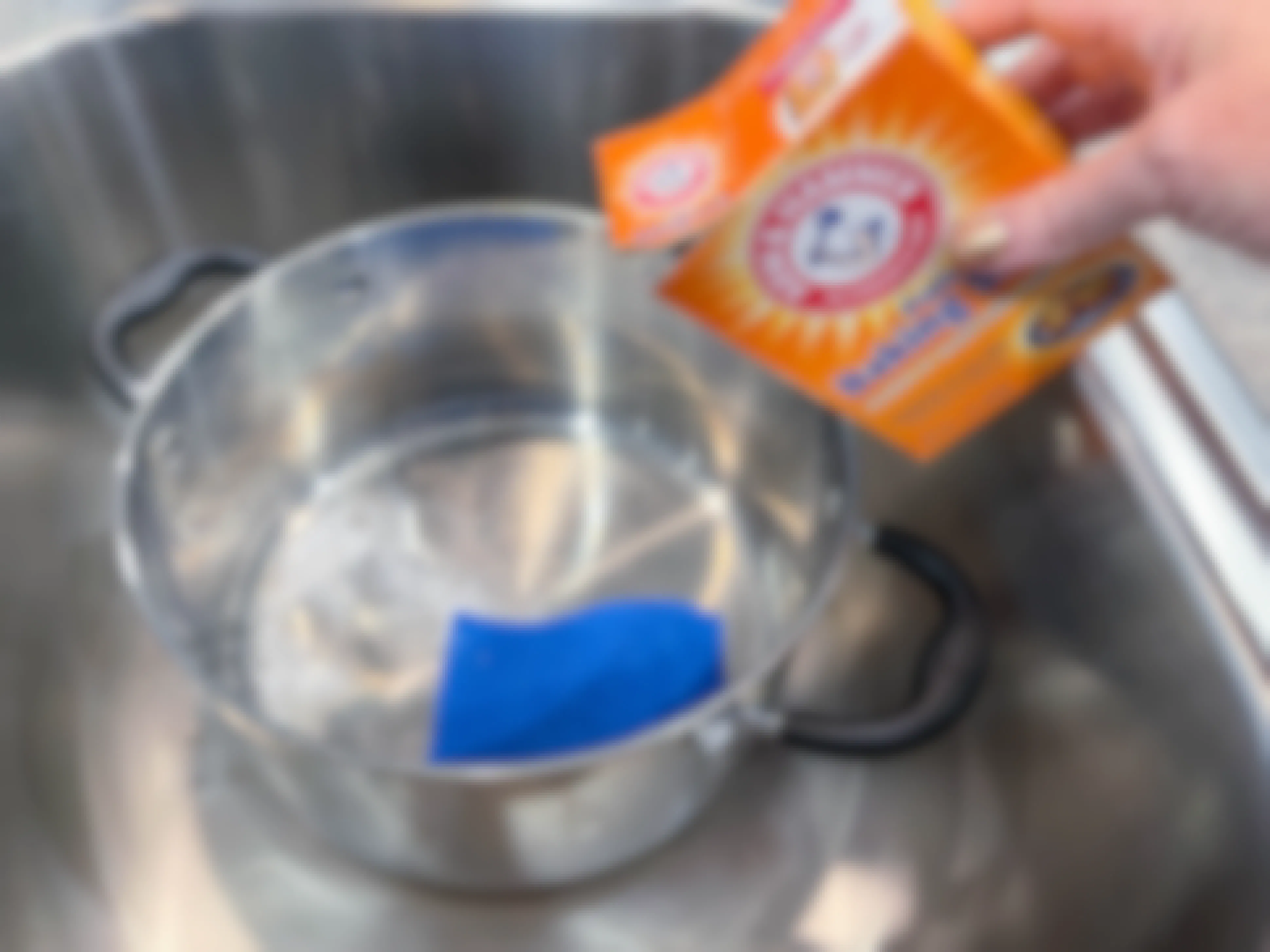person pouring baking soda in pot sitting in sink