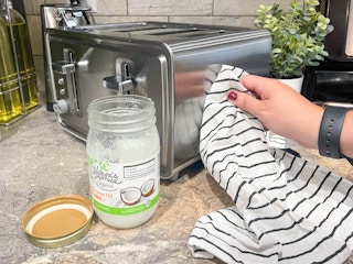 person using cloth to clean toaster with coconut oil