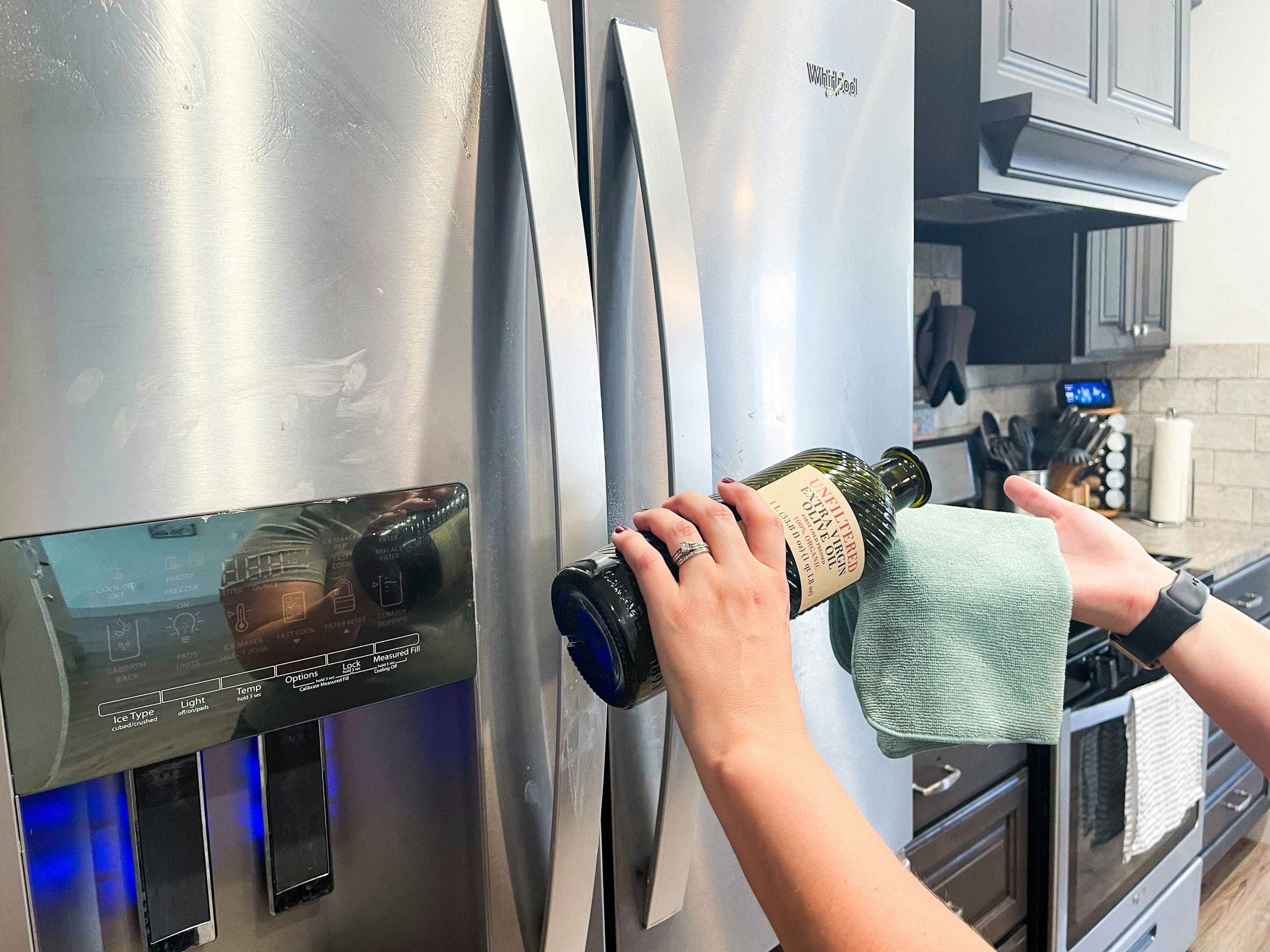 person pouring olive oil on cloth to clean fridge