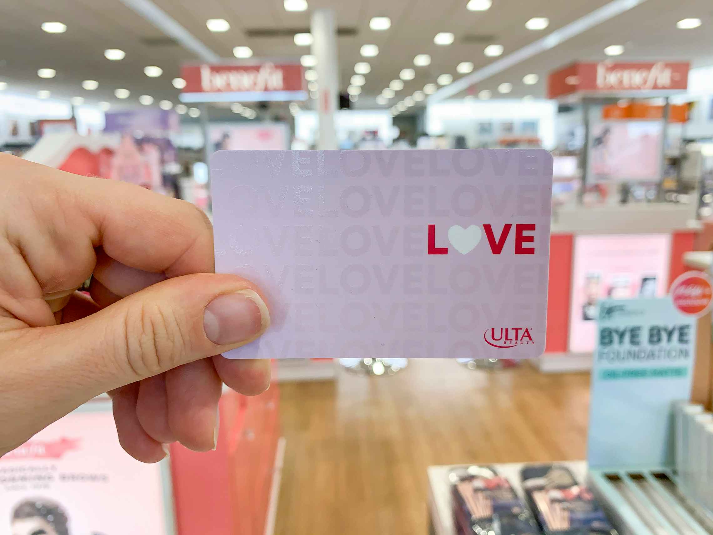 An ulta gift card with the word "Love" on the front held in a store.