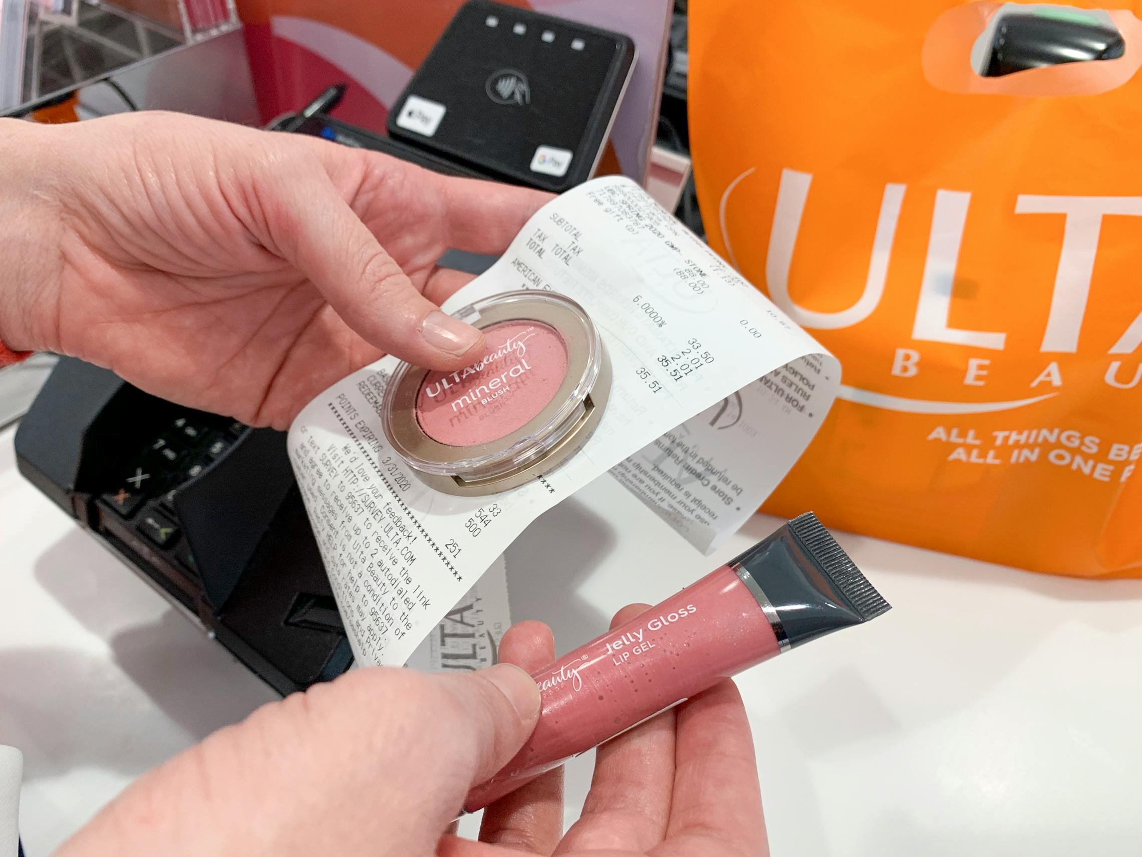 A woman holding a receipt and items to return at an ulta register.