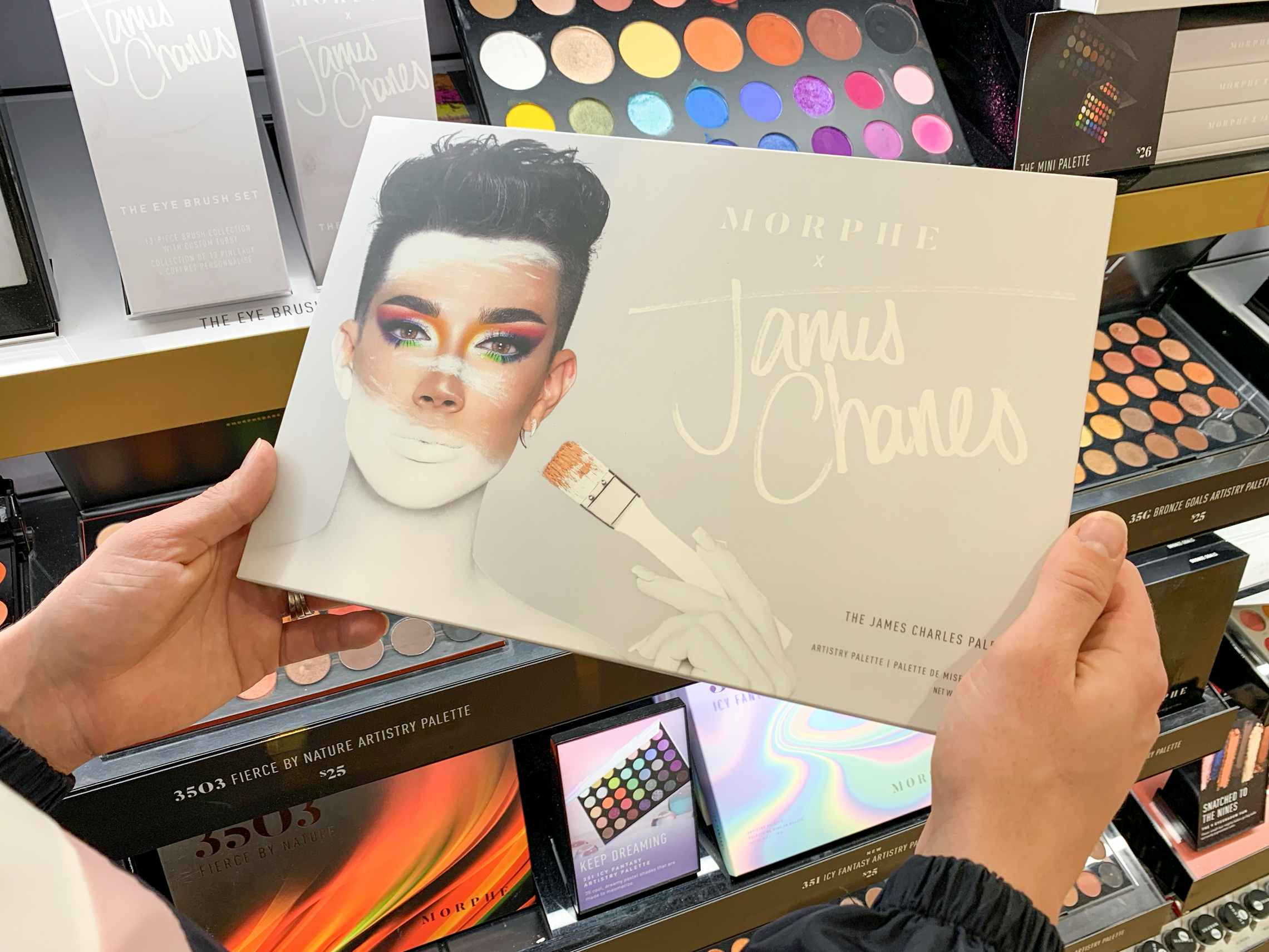 A woman looking at a Morphe James Charles makeup palette.