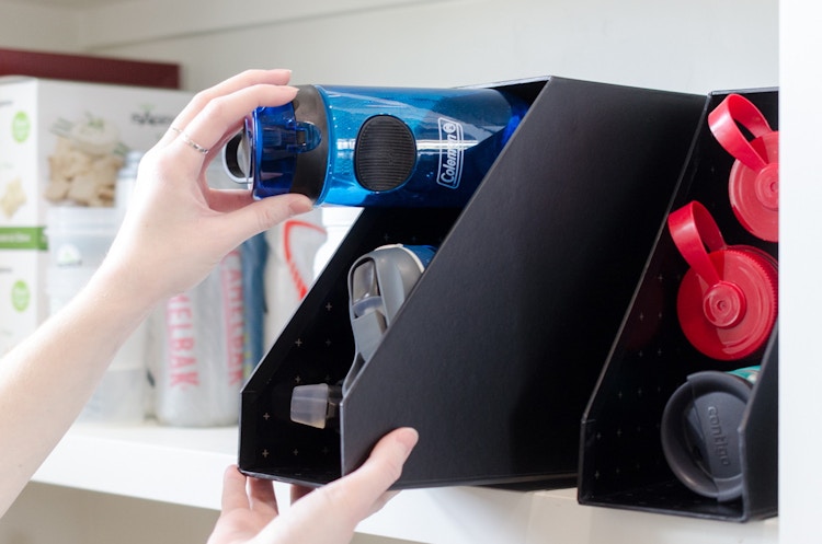 Someone organizing water bottles into file holders