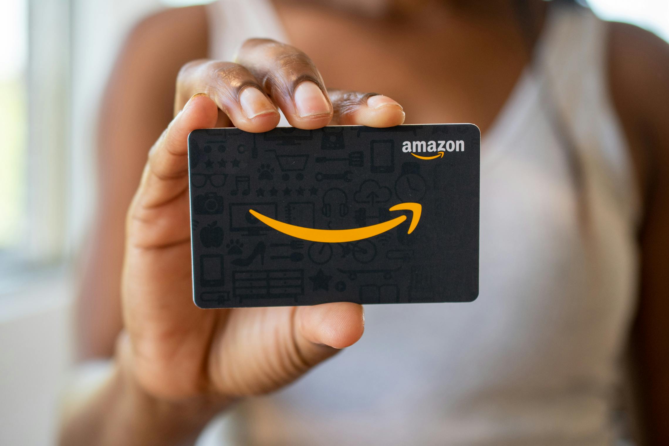 A woman holding an Amazon gift card.