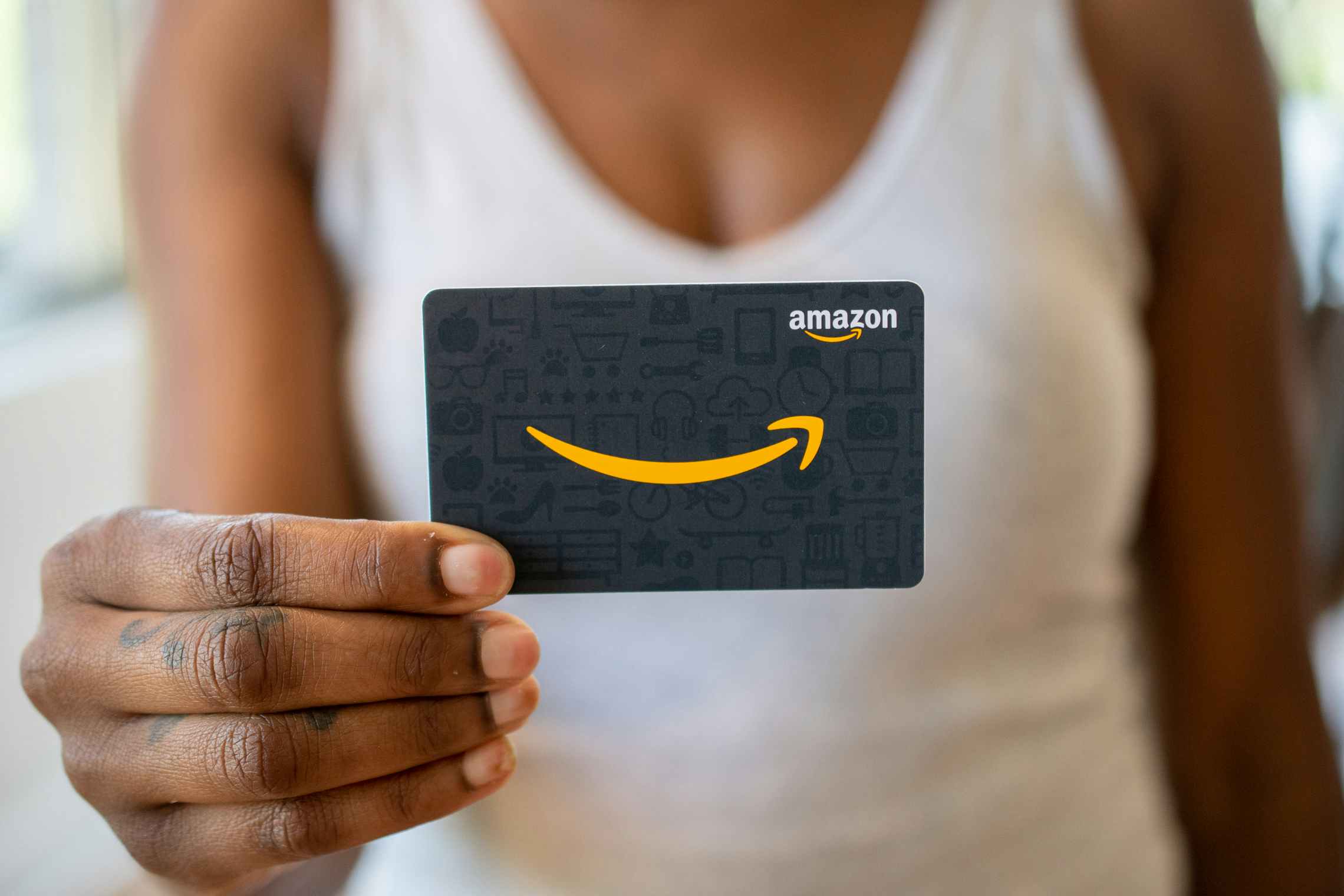 a woman holding up an amazon prime gift card