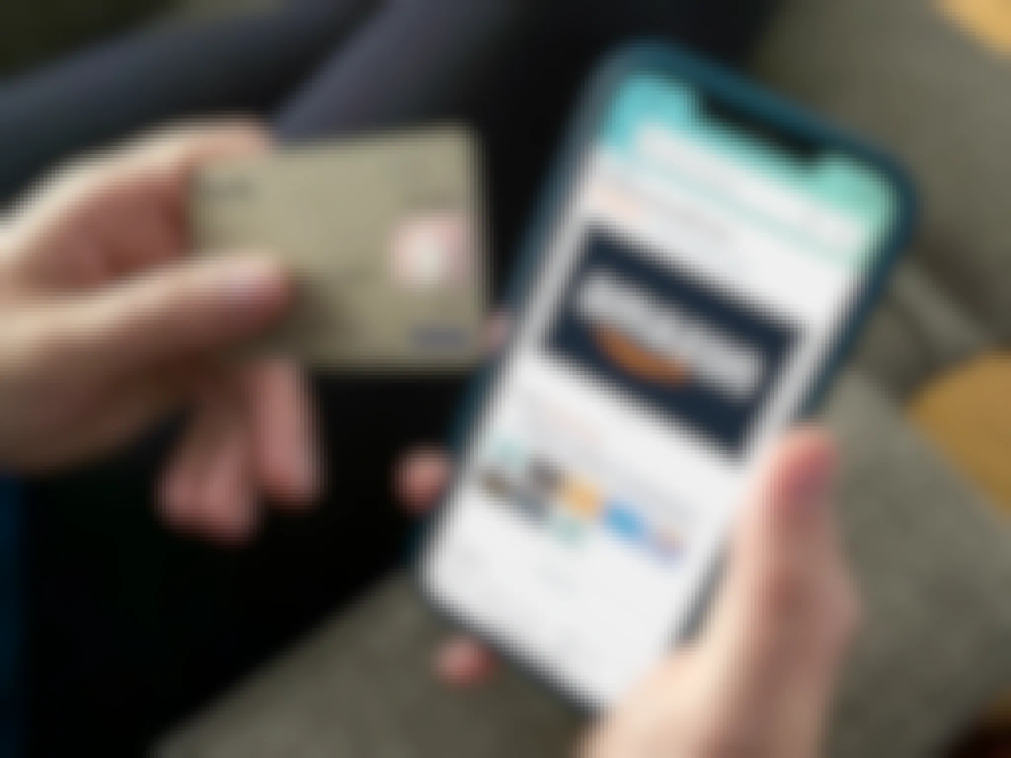 A person holding a visa gift card next to a cell phone open to an amazon gift card purchase page.