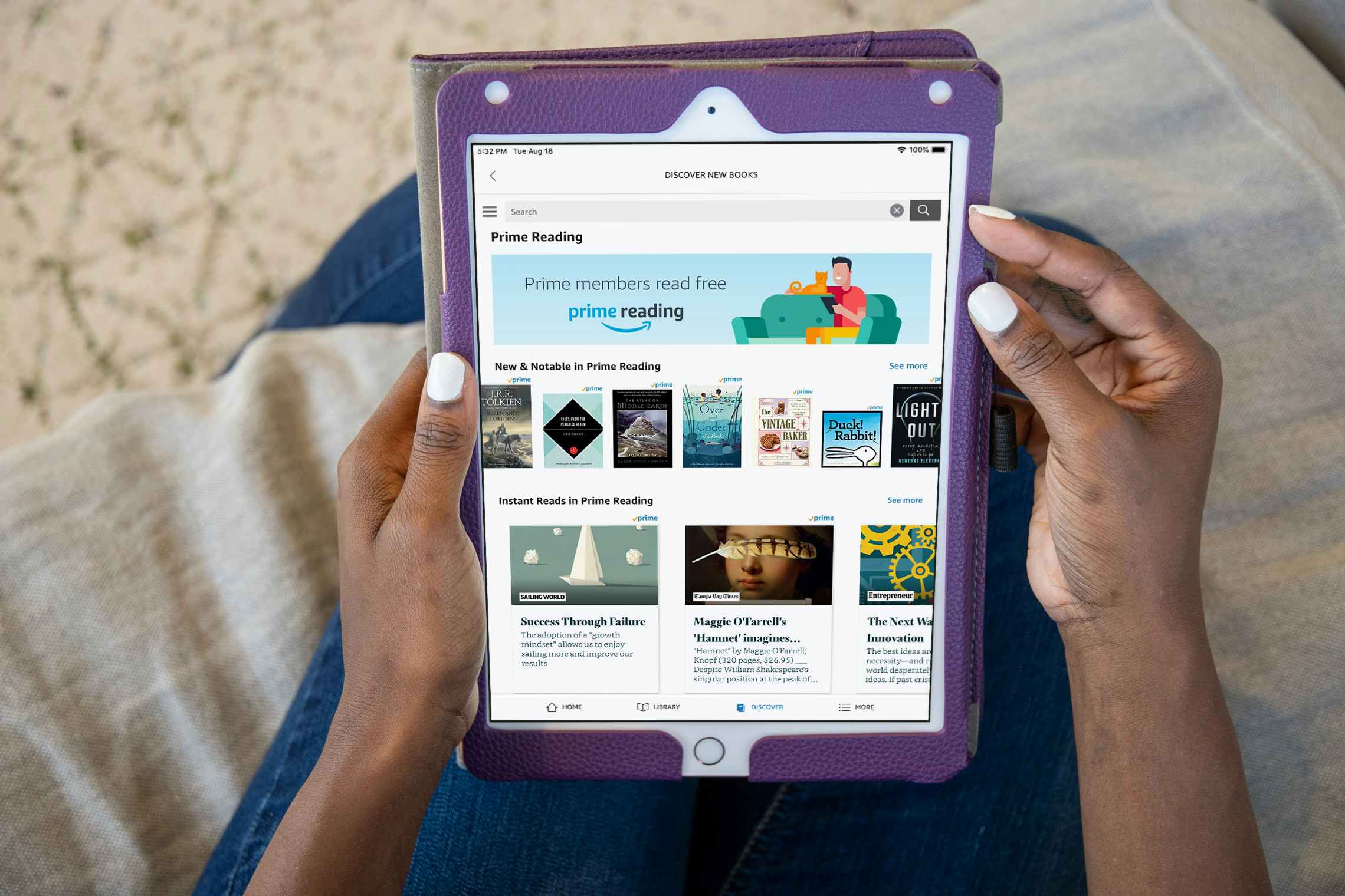 A woman sitting on a couch, holding an iPad which is displaying the Amazon website's page for Prime Reading.
