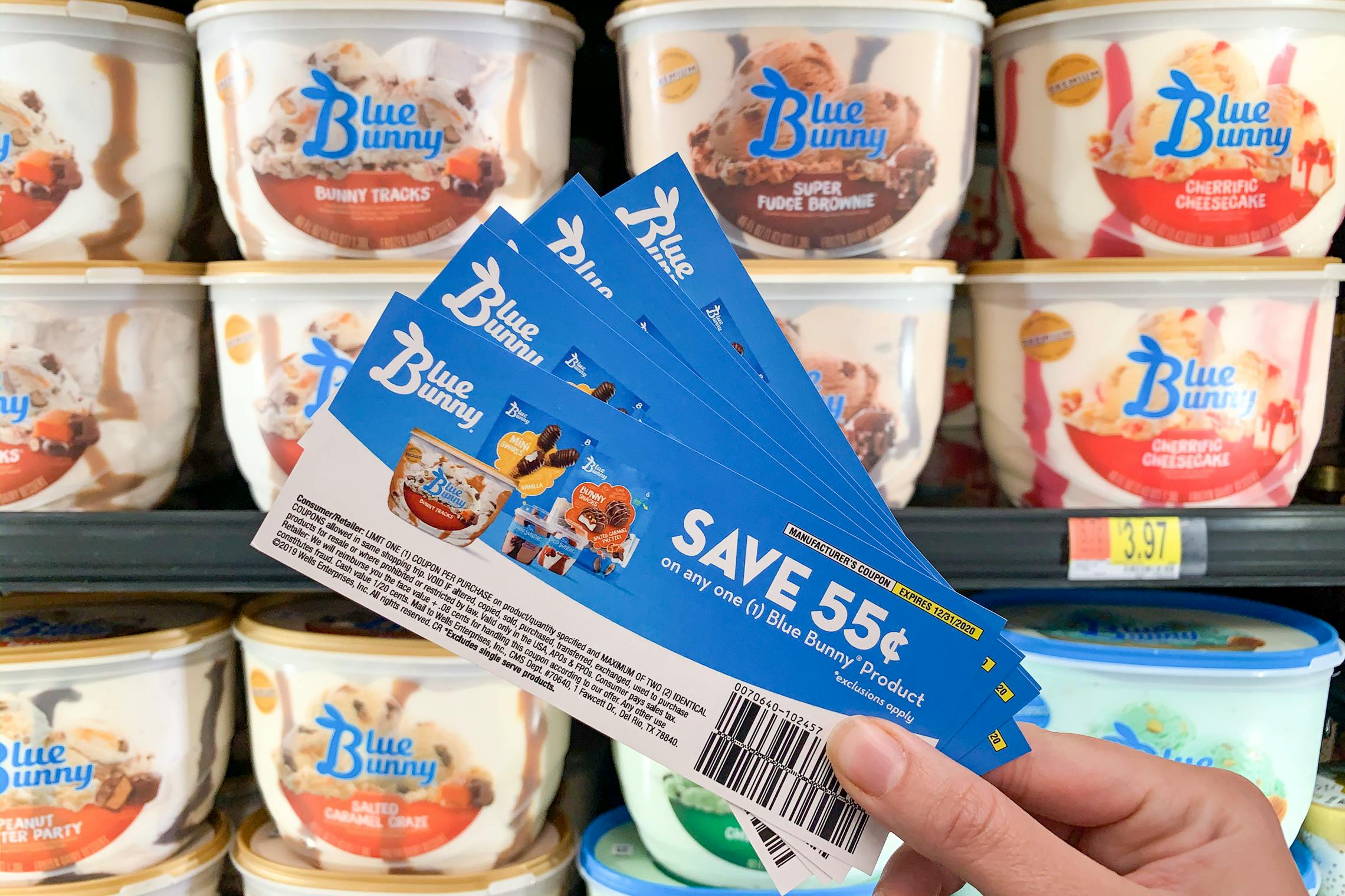 Blue Bunny Ice Cream coupons held in front of ice cream cooler in store.