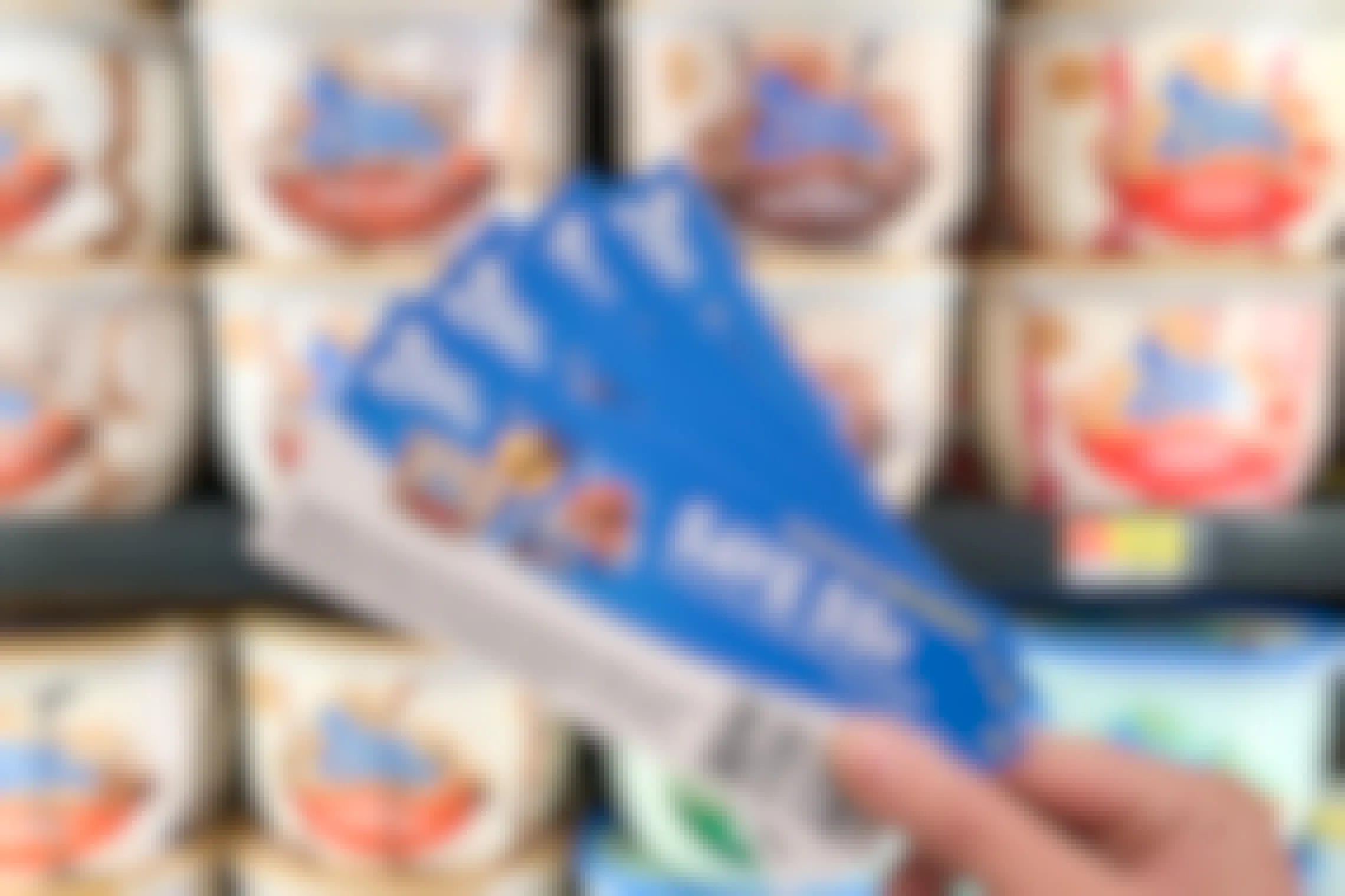 Blue Bunny Ice Cream coupons held in front of ice cream cooler in store.