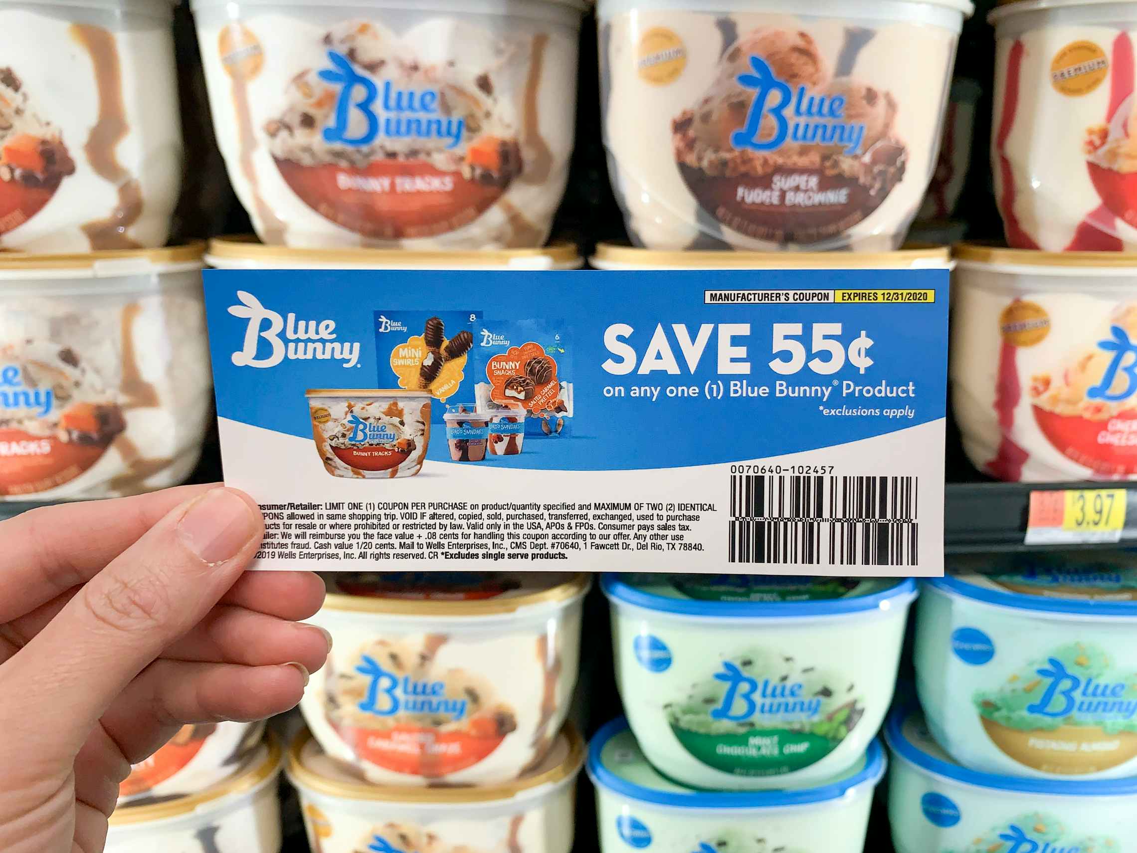 Blue Bunny Ice Cream coupon held in front of ice cream cooler in store.