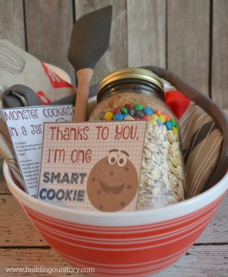 A mixing bowl with a jard of dry cookie ingredients in it, hot pads, a spatula, cookie recipe on a card and a thank you card in the front.