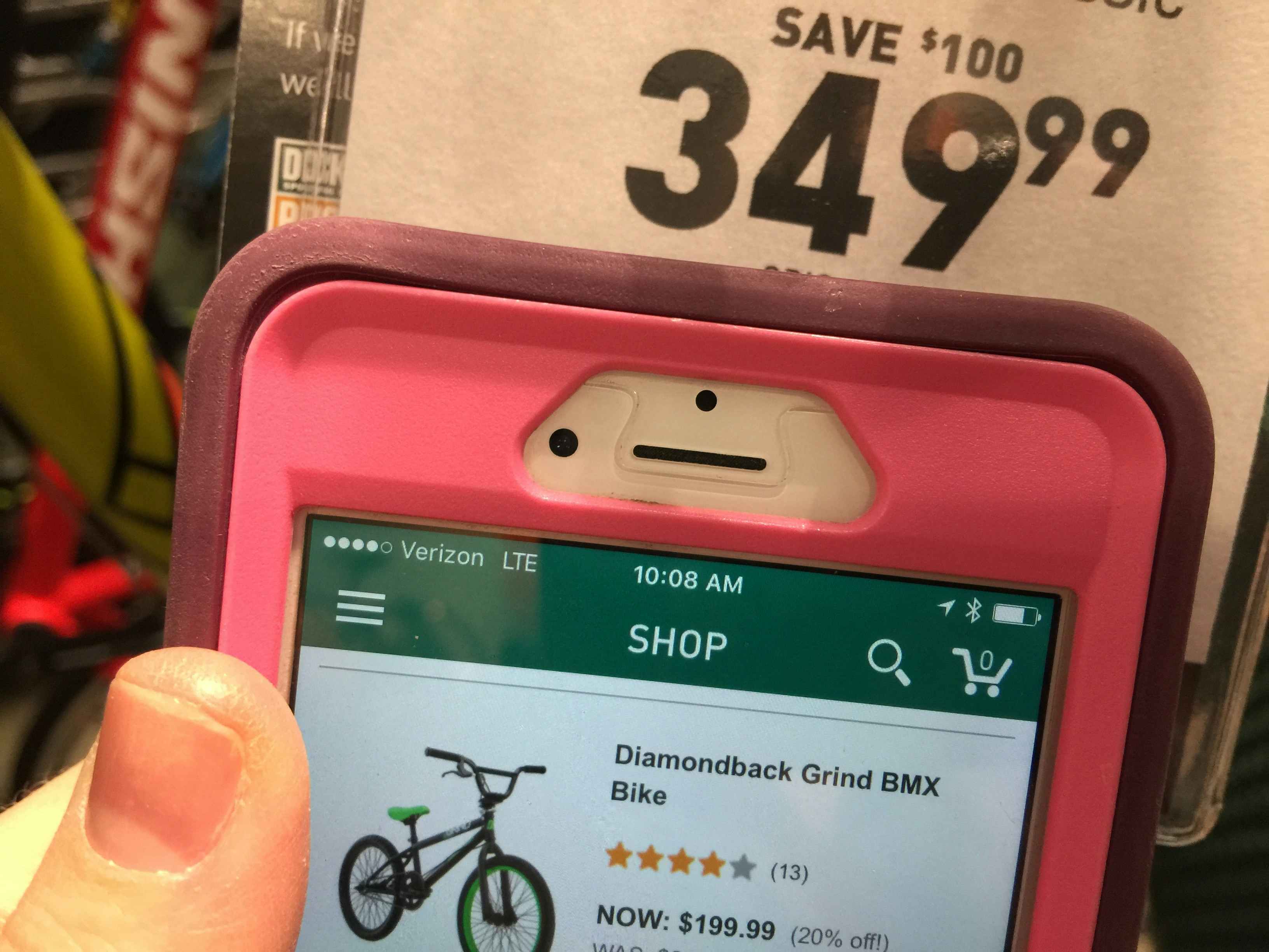 A close up of a price tag on a bike with a lower price pulled up on the Dick's app for the same item.
