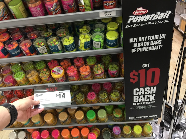 A person's hand showing the price tag for an endcap item with a sign advertising a rebate offer.