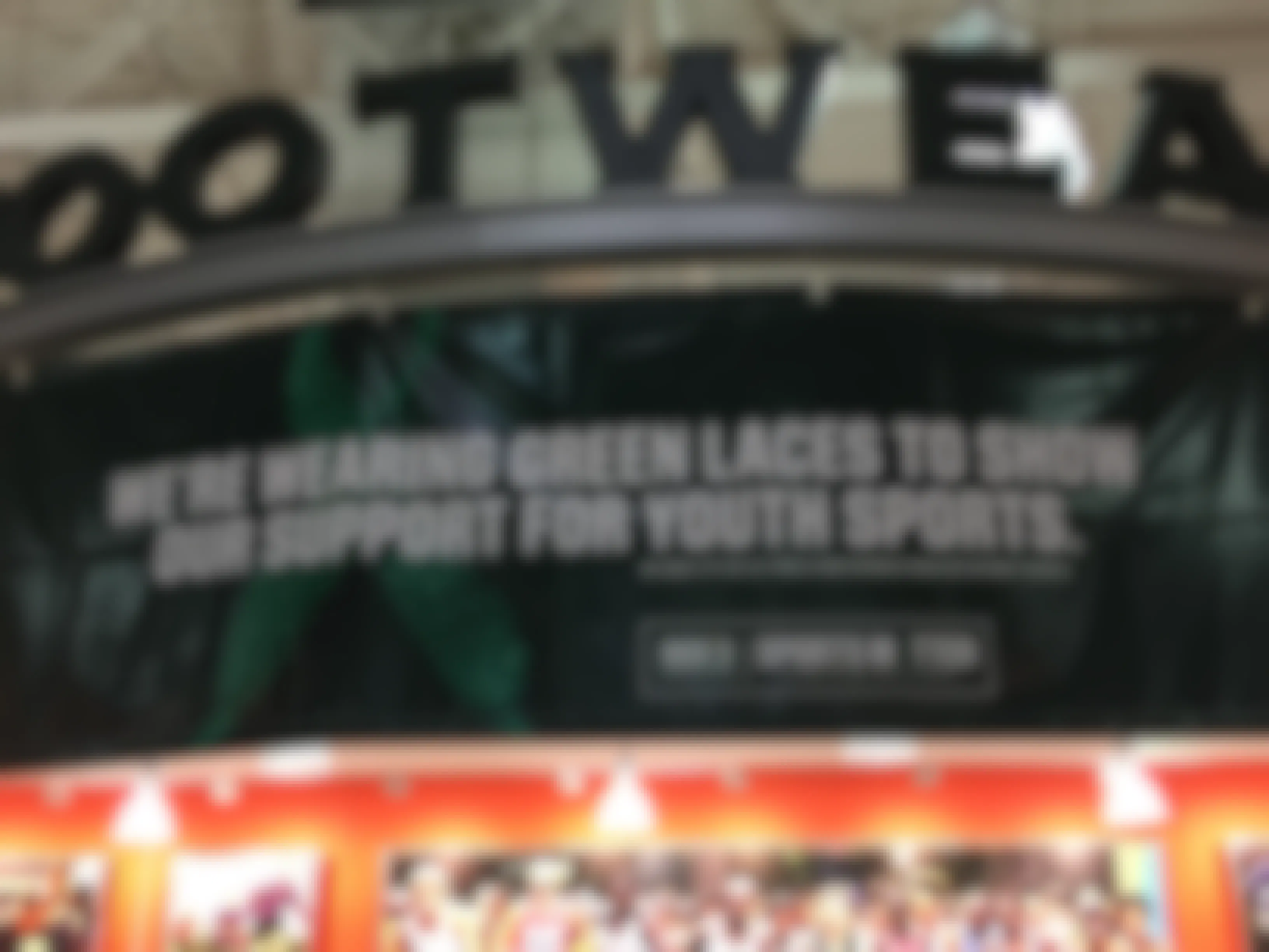 A banner inside a Dick's Sporting Goods store that reads, "We're wearing green laces to show our support for youth sports.