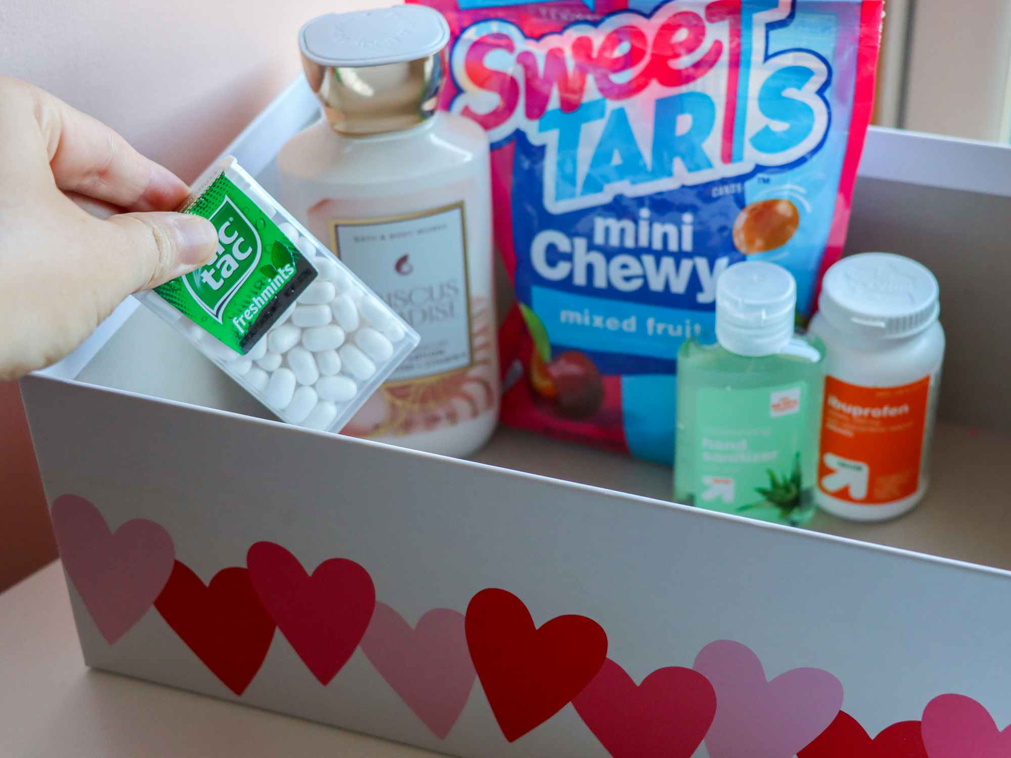 a person putting tic tacs into a box with other items