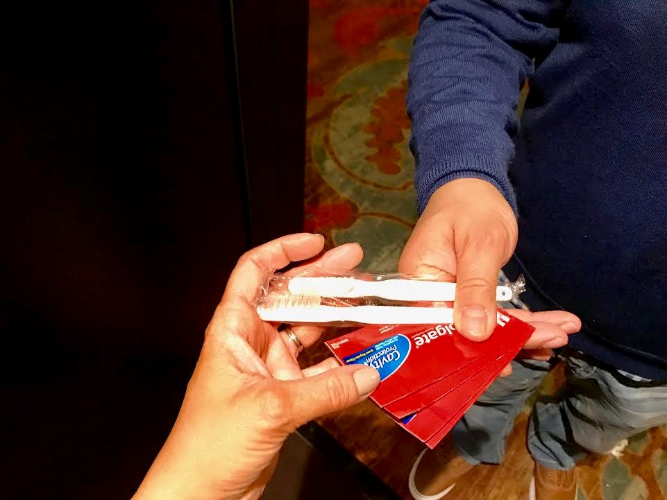A person handing another person two toothbrushes.
