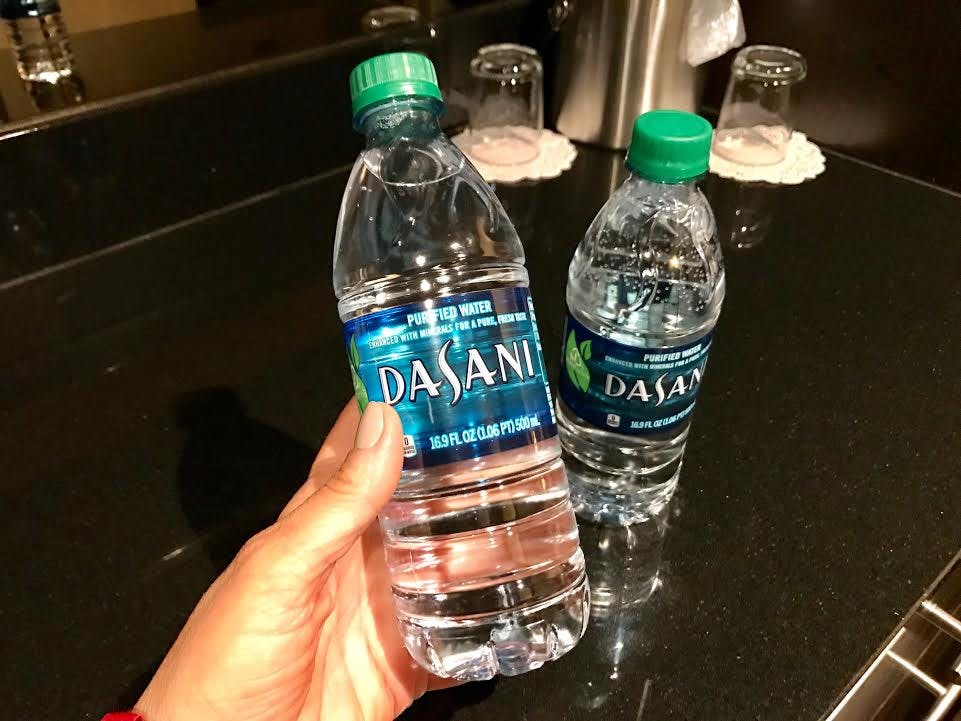 A person holding two Dasani water bottles.
