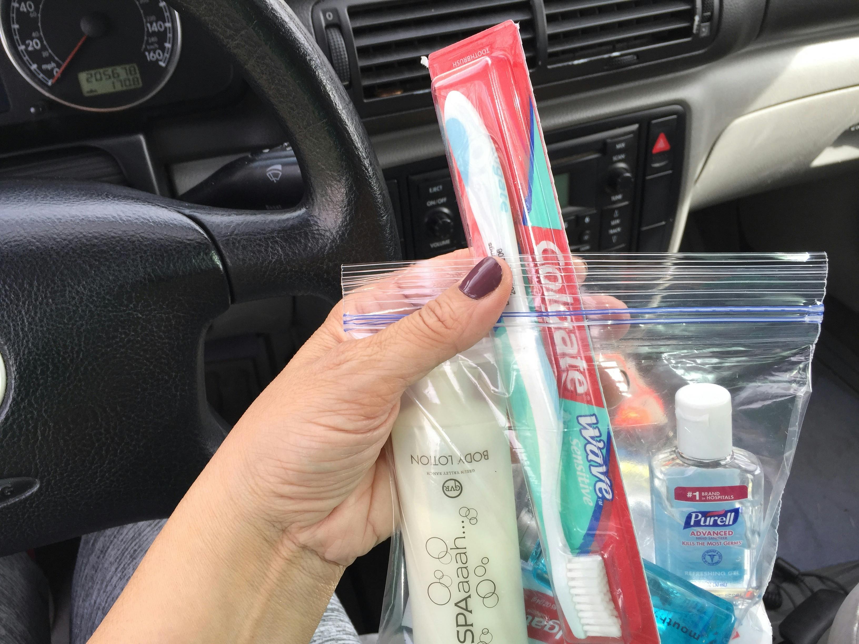 A person holding a zip bag with toothpaste and other toiletries.