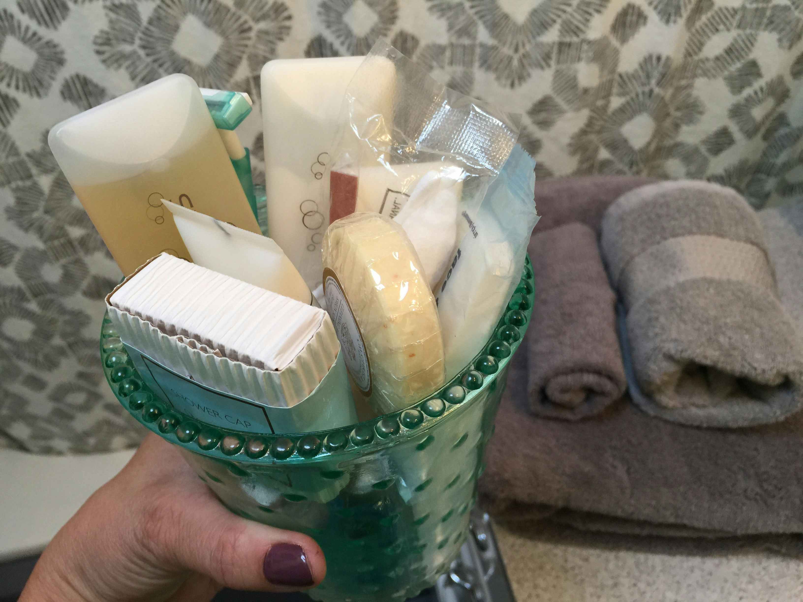A person holding a vase with soap and other toiletries in it.