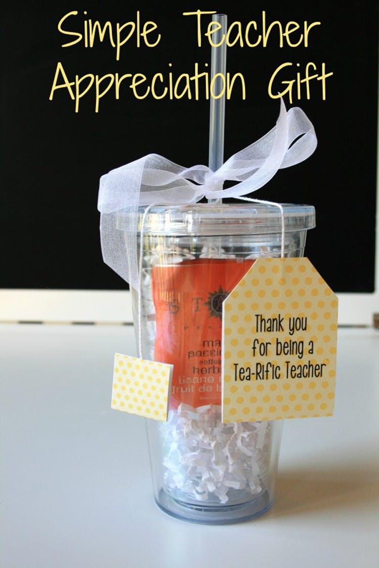 A clear plastic cup with straw and tea bags inside with a tag on the outside that reads thank you for being a tea-rific teacher and has a ribbon tied around the straw.