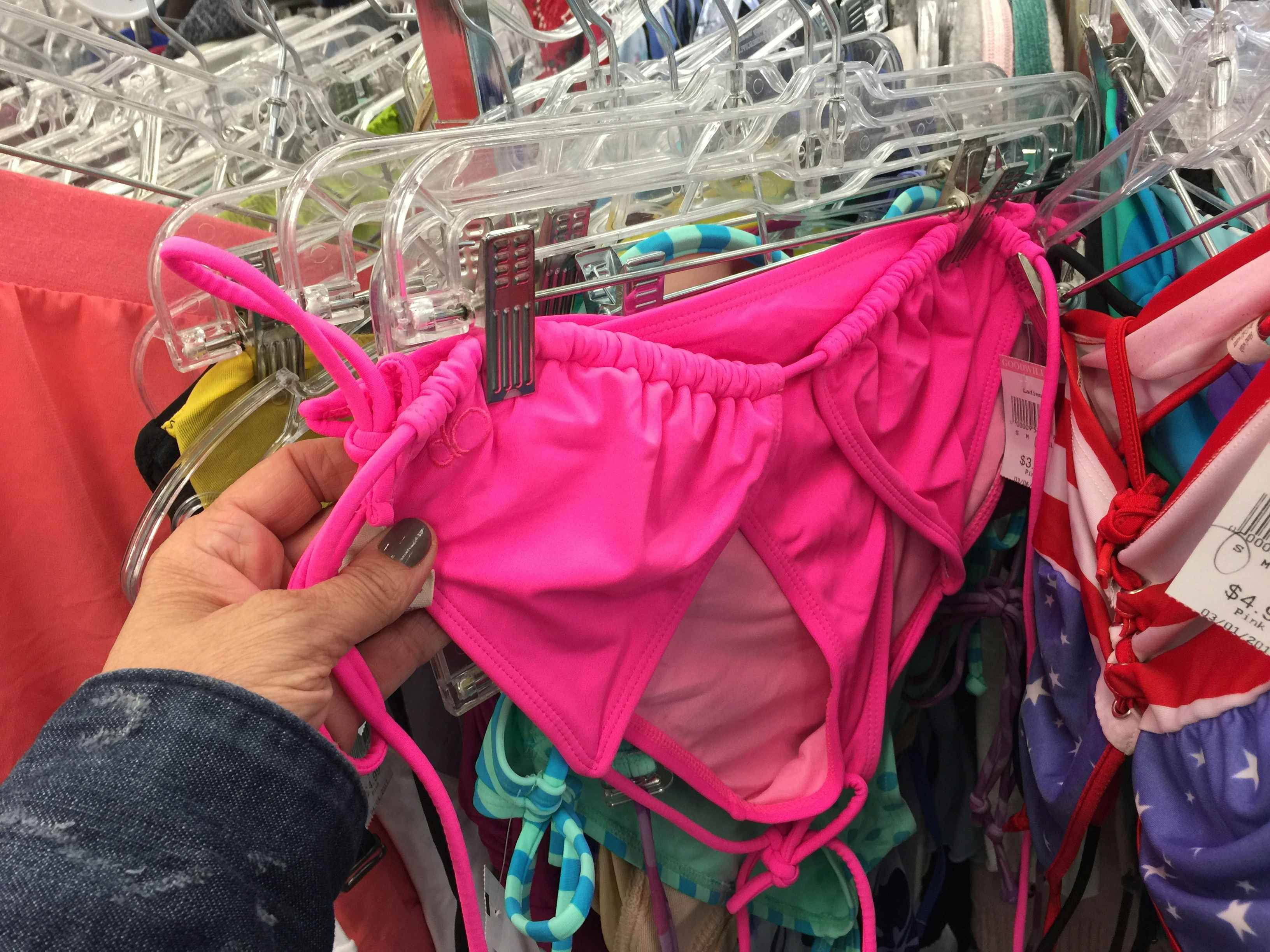 A person looking at a swimsuit on a rack at Goodwill