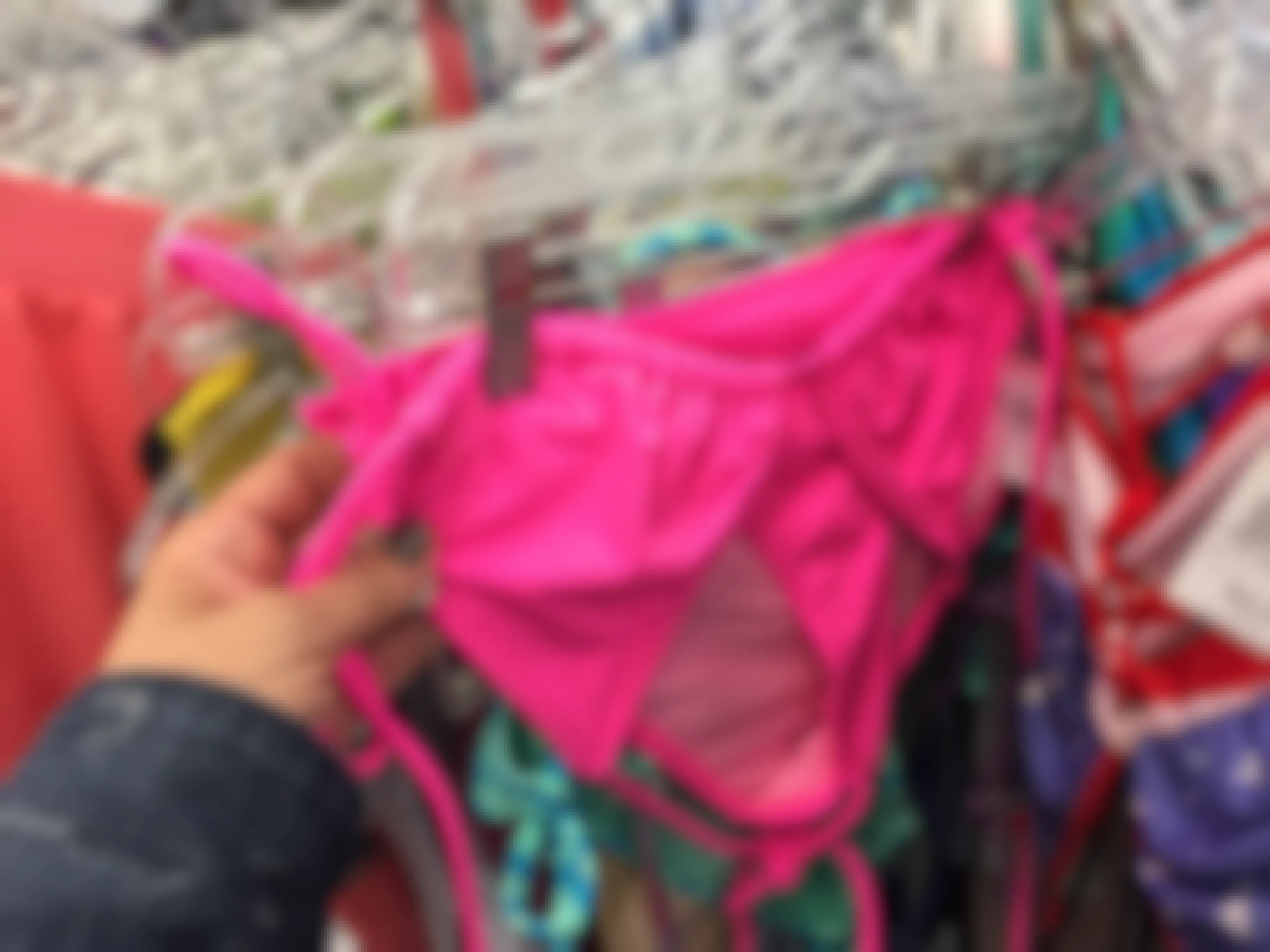 A person looking at a swimsuit on a rack at Goodwill