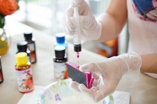 person filling an ink cartridge with ink